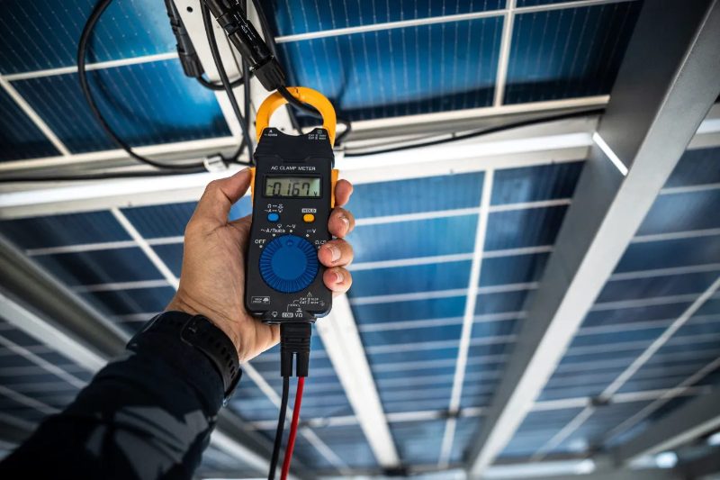 Technician measuring the grid connection voltage of a solar system